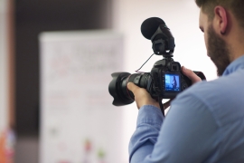 videographer-at-conference-seminar-taking-footage-and-recording-video-on-camera-SBI-322417620